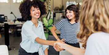 Heureuse femme d'affaires serrant la main d'un collègue sur le lieu de travail