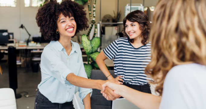 Heureuse femme d'affaires serrant la main d'un collègue sur le lieu de travail